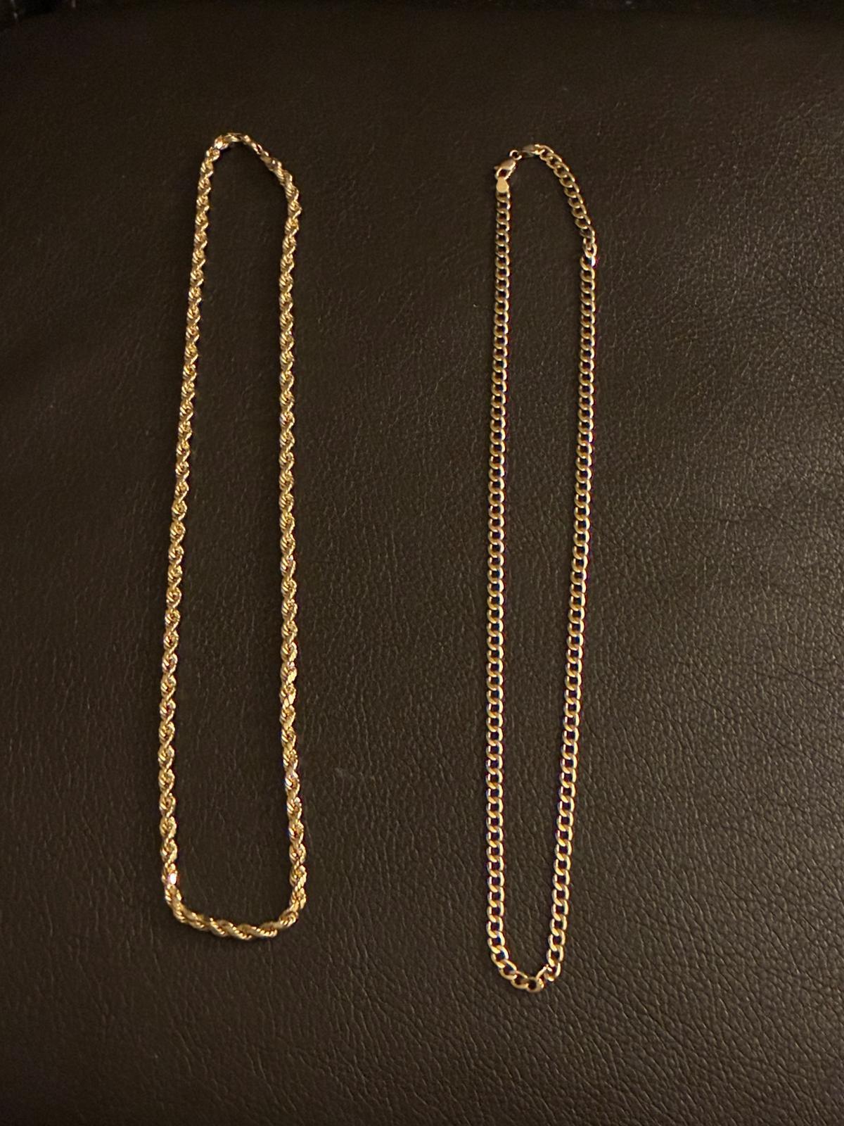 Two gold chains side by side on dark leather