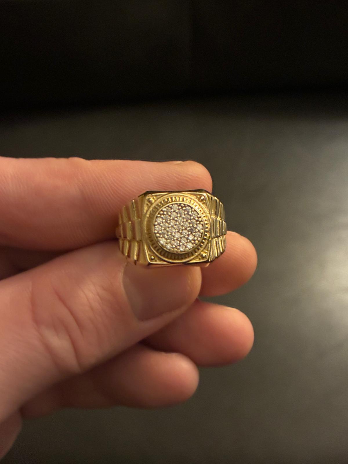 Gold ring with circular diamond cluster held by a hand