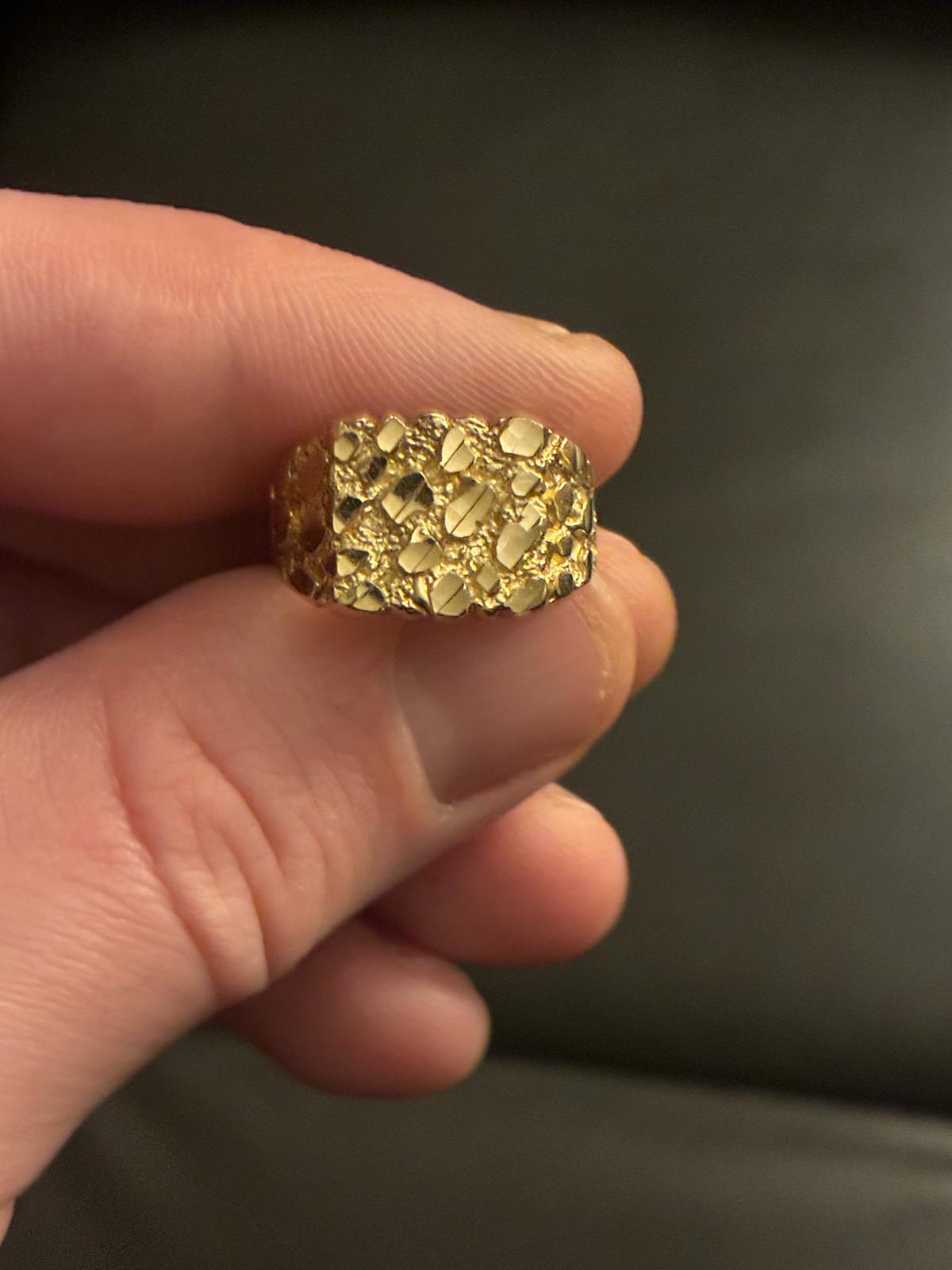 Textured nugget style gold band between fingers