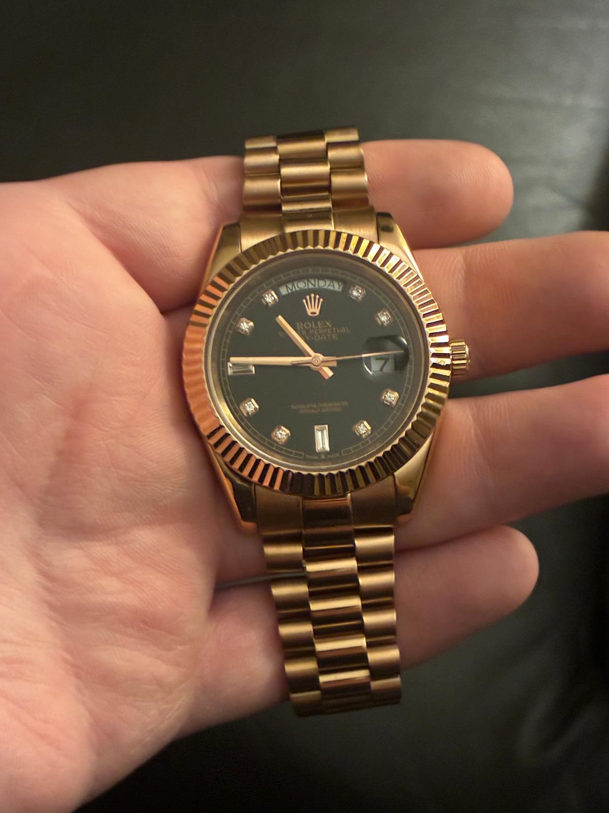Rose gold Rolex Day-Date with diamond hour markers held in a hand
