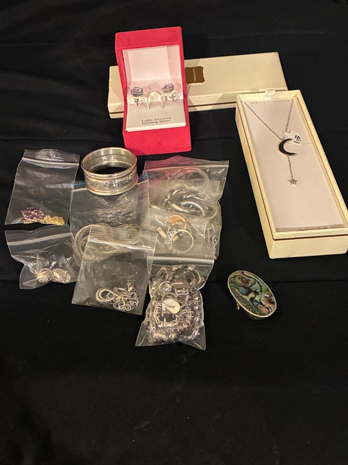 Sterling bracelet, bagged charms, and boxed jewelry spread on a black table